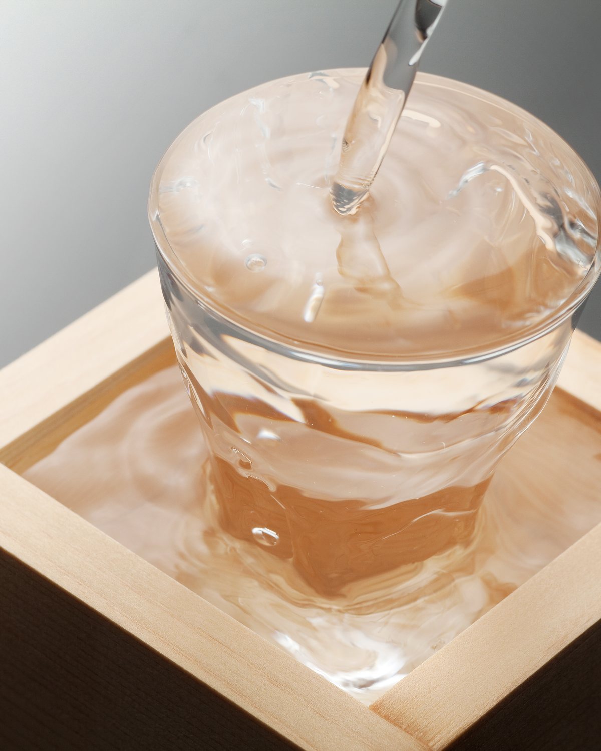 枡の中のグラスに注がれる日本酒